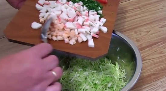 Кубиками нарезаем очищенные креветки, помидор, крабовые палочки и мелко рубим зелень