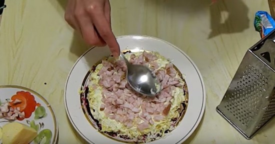 Поверх яиц выкладываем слой копчёного мяса